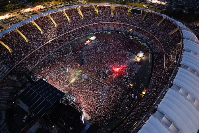 A packed stadium in Bari at night, seen from above, with the ATS logo